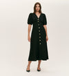 A woman models the Sarah Black Crepe Button Through Midi Tea Dress, featuring short puff sleeves, a V-neckline, and large gold front buttons. She pairs it with black pointed-toe heels against a plain background.