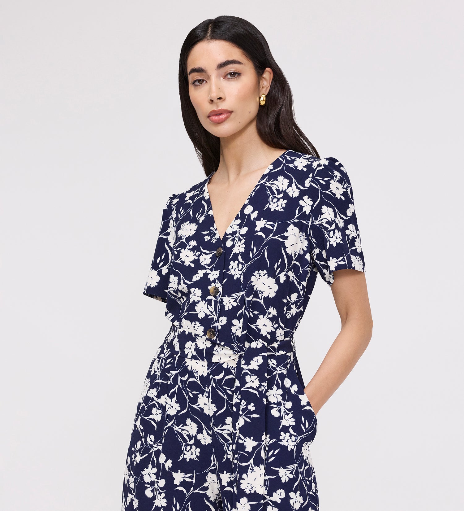 Woman wearing Uma Navy Floral Belted Wide Leg Jumpsuit on a light gray background