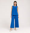 A woman faces forward in the Vallie Cobalt Round Neck Vest, a relaxed-fit, sleeveless blue top paired with matching wide-leg textured pants. She has straight dark hair, wears white low-heeled shoes, and stands against a plain light background.