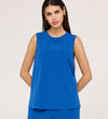 Woman with long dark hair wears the Vallie Cobalt Round Neck Vest and matching textured pants in bright blue, standing against a plain light background with her hands behind her back.