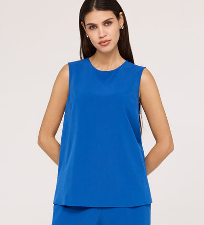 Woman with long dark hair wears the Vallie Cobalt Round Neck Vest and matching textured pants in bright blue, standing against a plain light background with her hands behind her back.