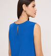 Woman with straight dark hair wearing the Vallie Cobalt Round Neck Vest, a sleeveless textured poly crinkle top with a keyhole button detail on the upper back. Shown from the back and side against a plain, light-colored background.