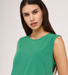 A woman with long dark hair wears the Vallie Green Round Neck Vest—a relaxed-fit, sleeveless top—and stands against a plain light background, gazing confidently at the camera.