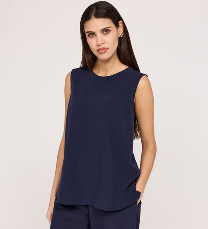 A woman with long dark hair and a neutral expression wears the Vallie Navy Round Neck Vest and matching relaxed-fit poly crinkle pants, standing against a plain light background with one hand in her pocket.