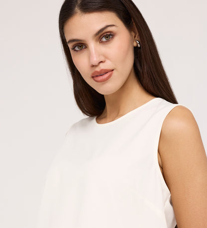 A woman with long, straight brown hair and light eyes wears pearl earrings and the Vallie Ivory Round Neck Vest, gazing neutrally at the camera against a plain light background.