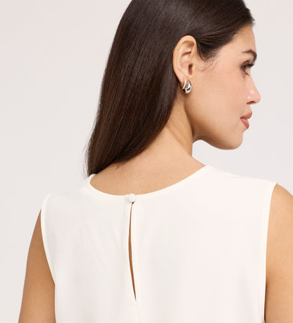 A woman with long brown hair, in silver hoop earrings and the Vallie Ivory Round Neck Vest—a sleeveless, textured shell top with relaxed fit and back button keyhole—is shown from behind and in profile.